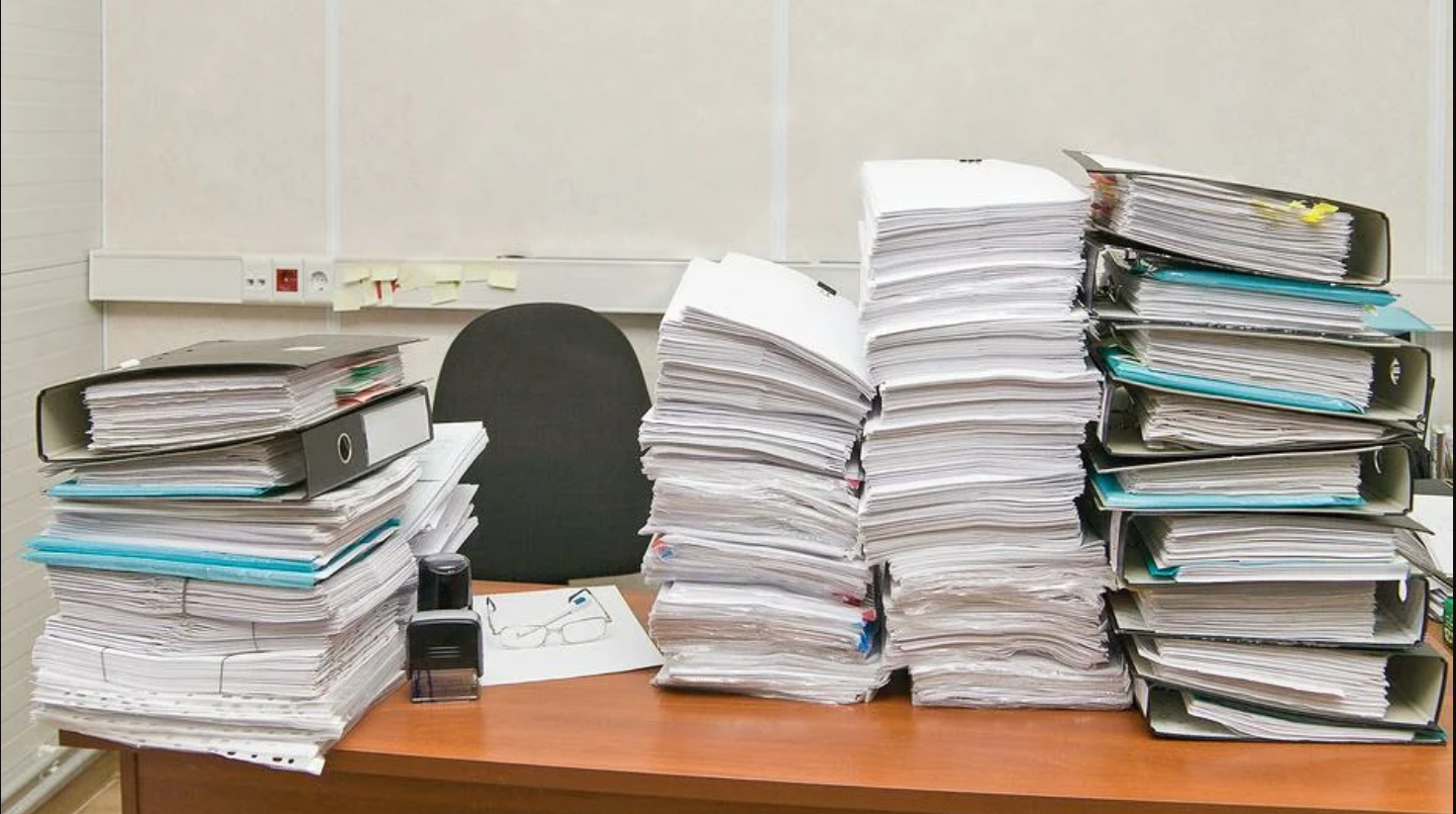 Много бумаг на столе. Стопка бумаг на столе. Куча бумаг на столе. Стол заваленный бумагами. Много бумаги.